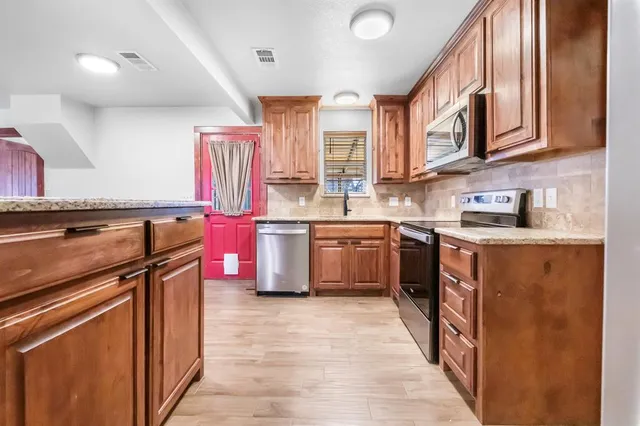 a kitchen with stainless steel appliances granite countertop a stove a sink dishwasher and a refrigerator
