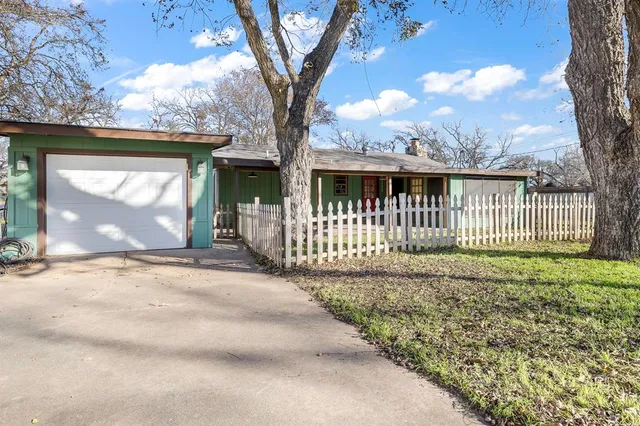 a view of a house with a small yard and a large tree
