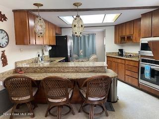 146 Bimini Road Cocoa Beach, FL 32931 - Photo 6 of 37 a kitchen with granite countertop a table chairs stove and cabinets