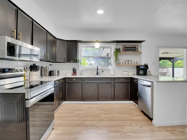 a large kitchen with stainless steel appliances granite countertop a stove sink and cabinets