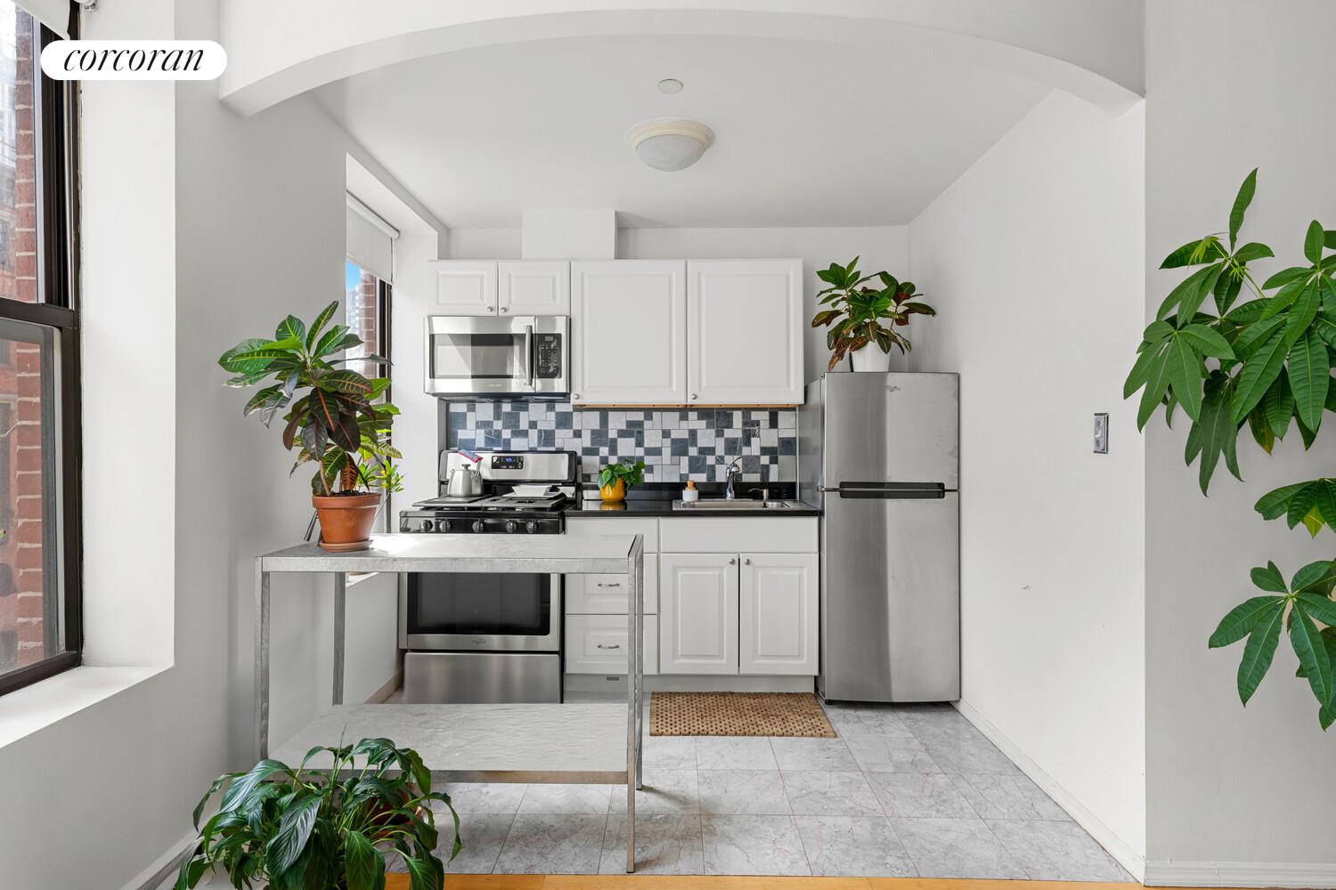 183 Duane Street Manhattan, NY 10013 - Photo 6 of 19 a kitchen with white cabinets and potted plant