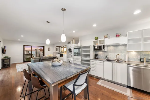 a kitchen with kitchen island a dining table chairs cabinets and stainless steel appliances