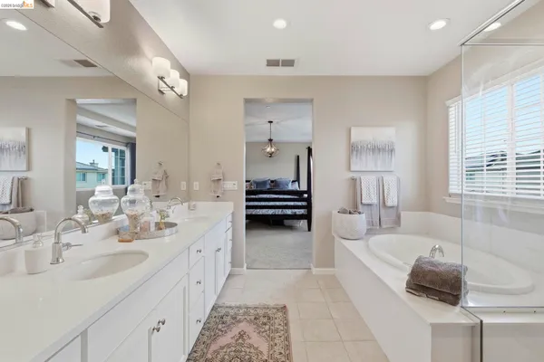 a en suite bathroom with a double vanity sink tub and mirror