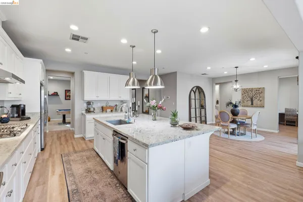 a large kitchen with stainless steel appliances granite countertop a lot of counter space and wooden floors
