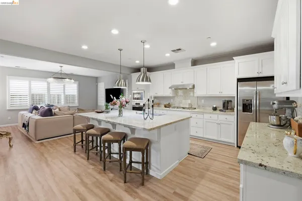 a large white kitchen with lots of counter space dining table and stainless steel appliances