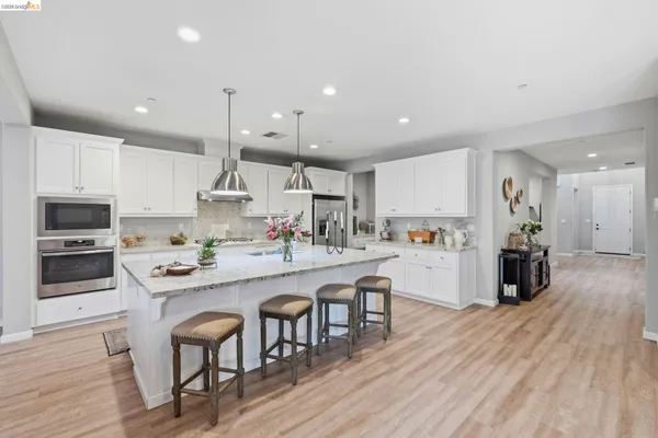 a kitchen with stainless steel appliances granite countertop a table chairs sink and cabinets