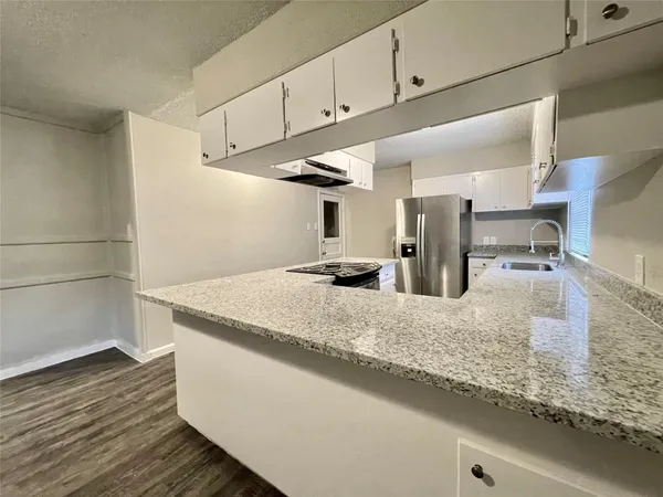 a kitchen with granite countertop sink stove and cabinets