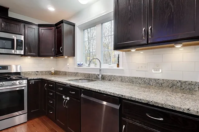 a kitchen with granite countertop stainless steel appliances wooden cabinets and a sink
