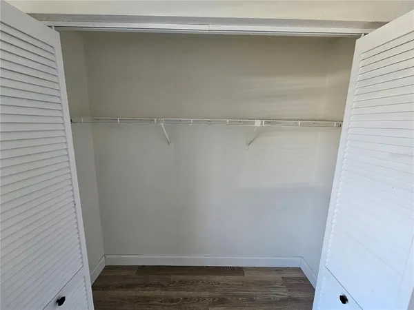 a view of a hallway with wooden floor and a cabinet