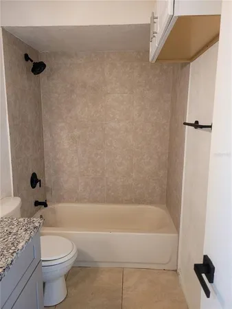 a bathroom with a granite countertop sink a toilet and bathtub
