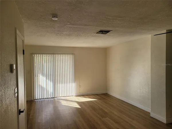 a view of an empty room with wooden floor and a window