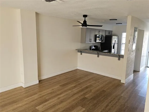a kitchen with granite countertop a refrigerator and a wooden floor