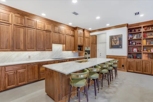 a kitchen with stainless steel appliances granite countertop a table chairs sink and cabinets