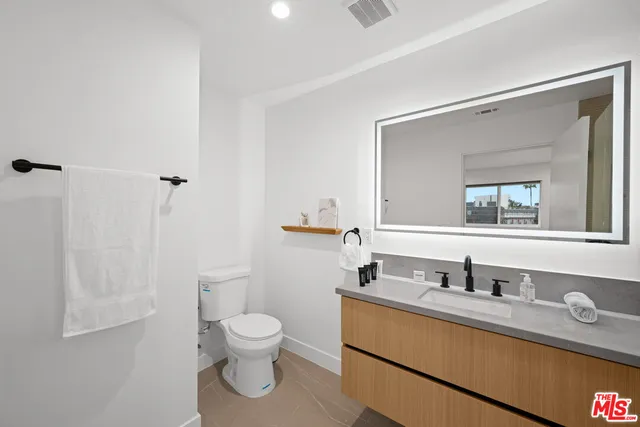 a bathroom with a granite countertop toilet sink and mirror