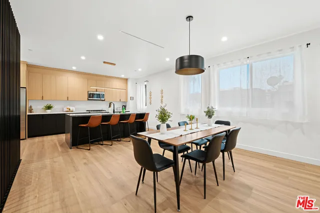 a kitchen with stainless steel appliances kitchen island granite countertop a table chairs and a refrigerator