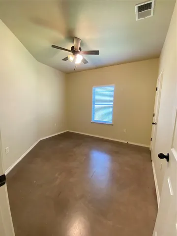 an empty room with a ceiling fan and window