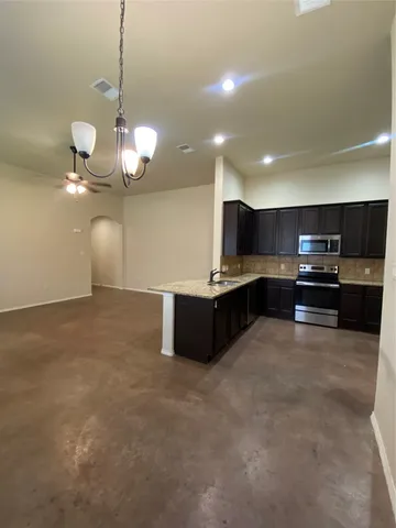 a large kitchen with stainless steel appliances kitchen island granite countertop a stove and a sink with chandelier