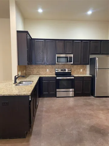 a kitchen with a sink a stove a refrigerator and cabinets