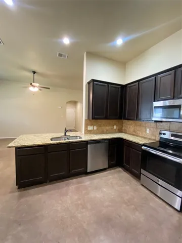 a kitchen with granite countertop a stove a sink and a refrigerator