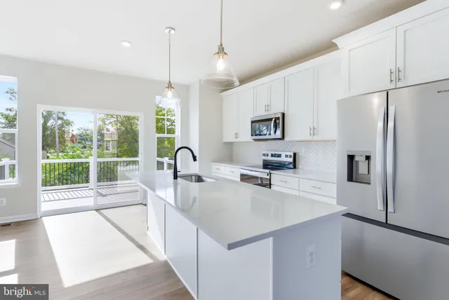 a kitchen with a refrigerator a stove top oven and a large window