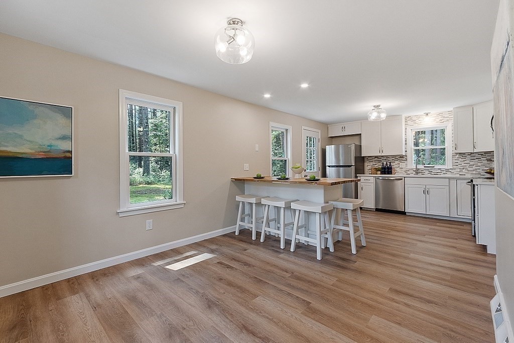 43 R Beaver Brook Road Westford, MA 01886 - Photo 7 of 42 a kitchen with stainless steel appliances kitchen island granite countertop a stove top oven a sink dishwasher a dining table and chairs with wooden floor