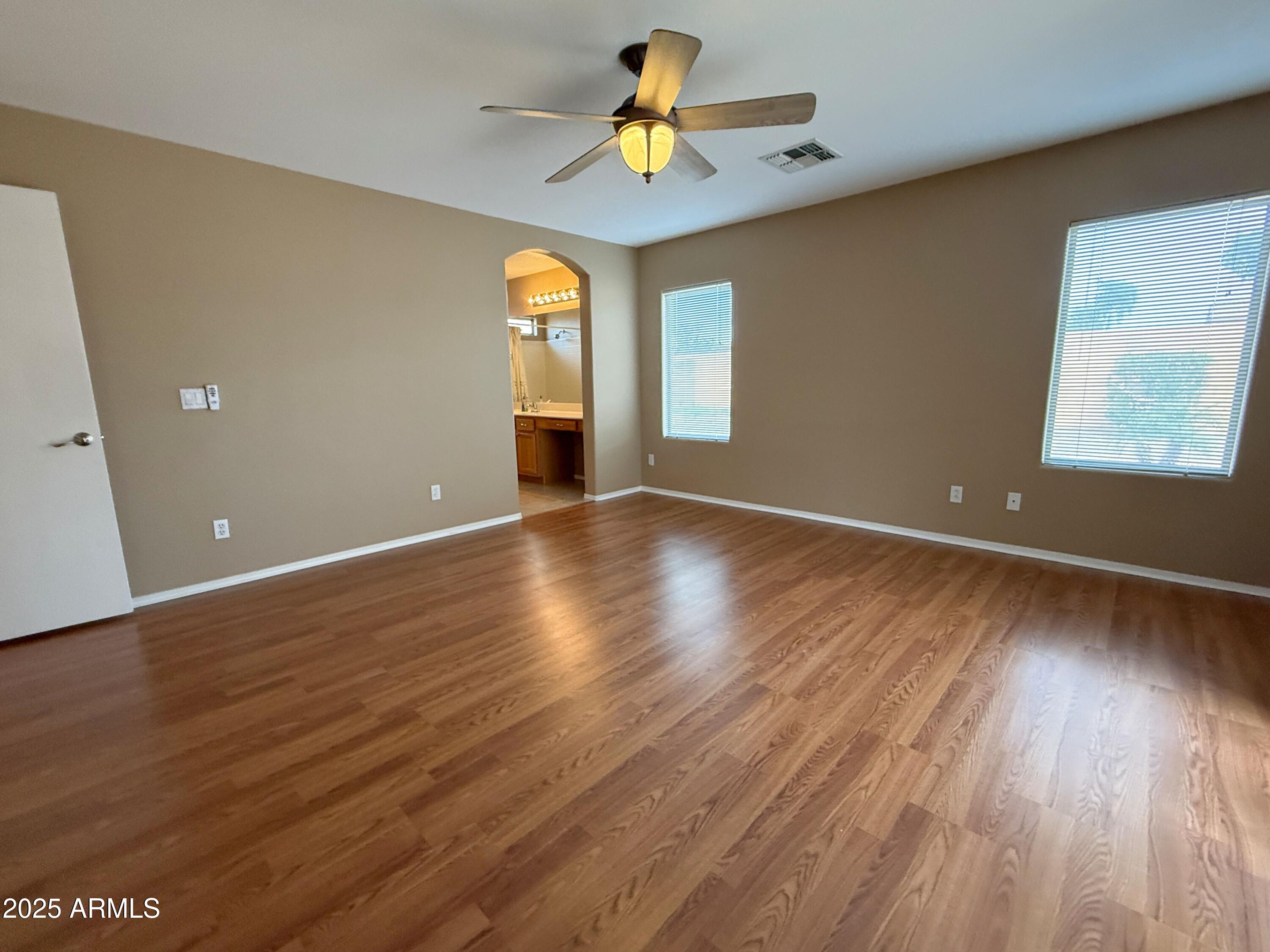3838 East Derringer Way Gilbert, AZ 85297 - Photo 11 of 24 an empty room with wooden floor chandelier fan and windows