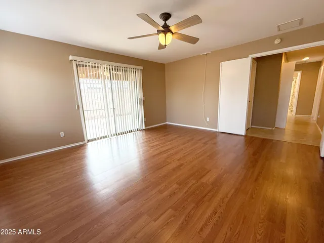 a view of empty room with wooden floor and fan