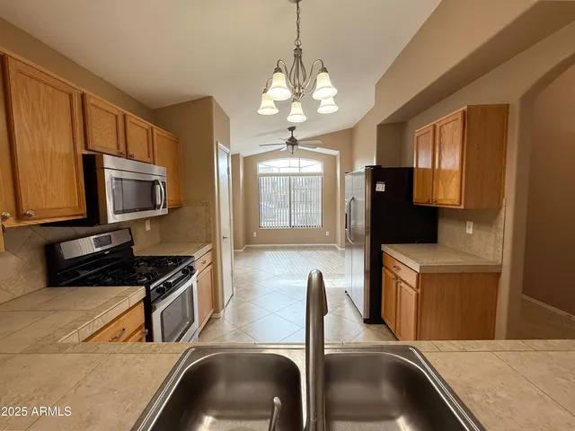 a kitchen with stainless steel appliances granite countertop a refrigerator a stove top oven a sink dishwasher and wooden cabinets