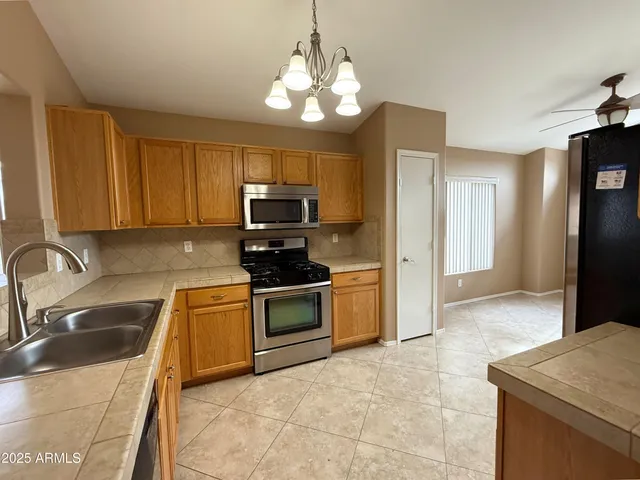 a kitchen with stainless steel appliances granite countertop a sink a stove a refrigerator cabinets and a counter top space