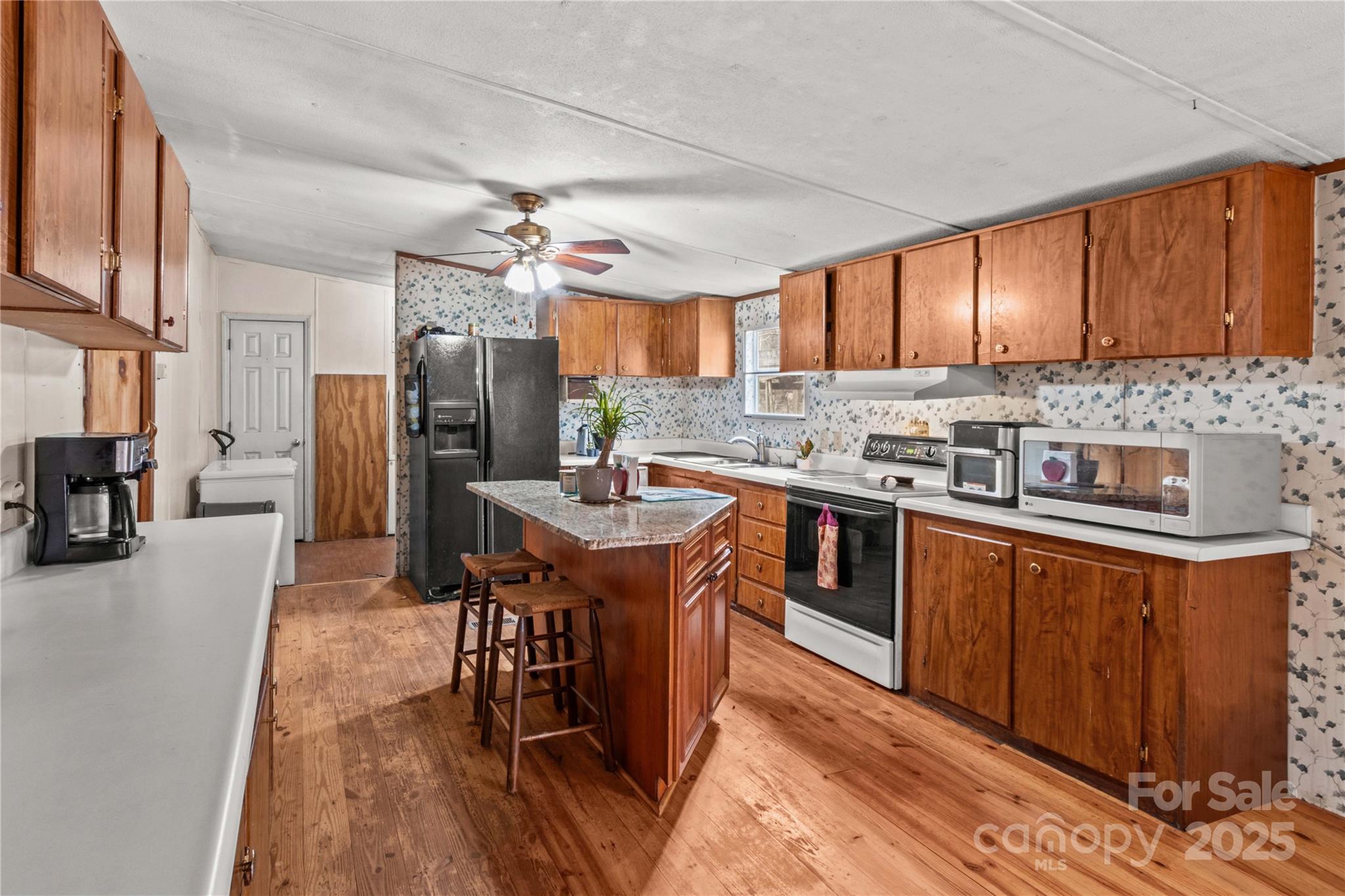 338 Piney Grove Road Harmony, NC 28634 - Photo 22 of 44 a kitchen with stainless steel appliances granite countertop a stove a sink dishwasher a refrigerator and a dining table with wooden floor
