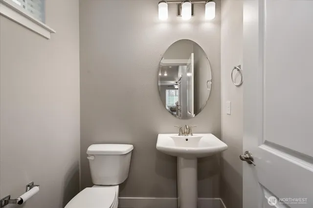 a bathroom with a toilet a sink and mirror