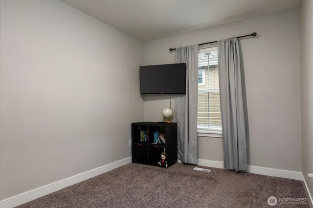 a view of an empty room with tv and a window