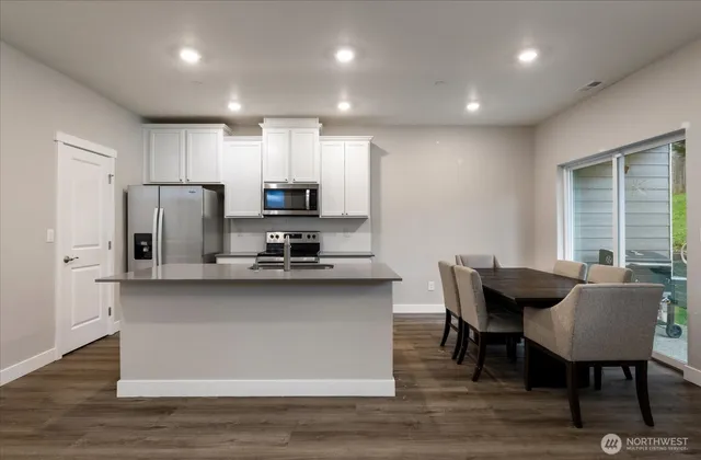 a kitchen with stainless steel appliances granite countertop a kitchen island hardwood floor sink stove dining table and chairs