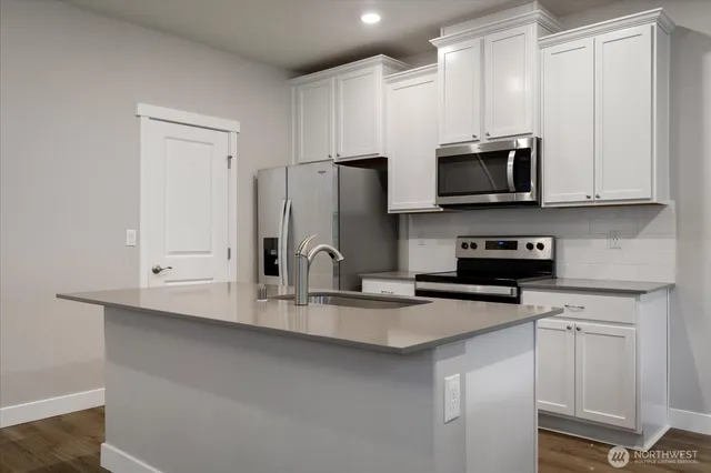 a kitchen with stainless steel appliances a sink a stove a microwave and cabinets