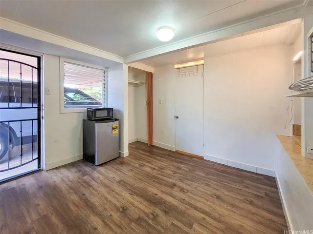 a view of empty room with wooden floor and window
