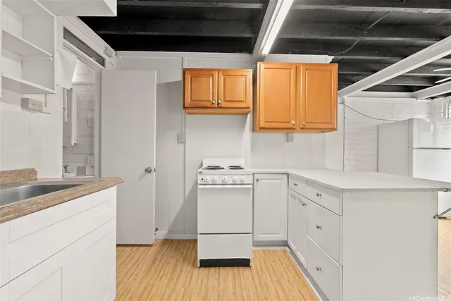 a kitchen with a sink a wooden floor and white stainless steel appliances