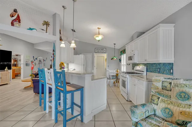 a kitchen with stainless steel appliances kitchen island granite countertop a dining table chairs and a refrigerator