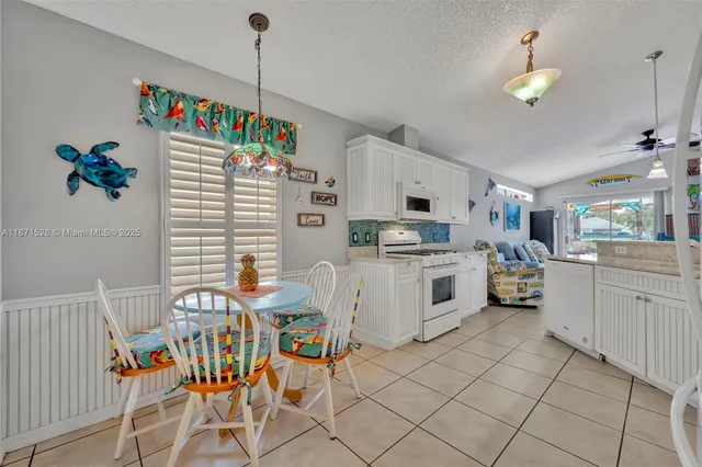a white kitchen with stainless steel appliances granite countertop a stove a sink and a refrigerator