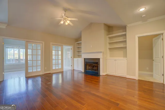 an empty room with wooden floor fireplace and windows