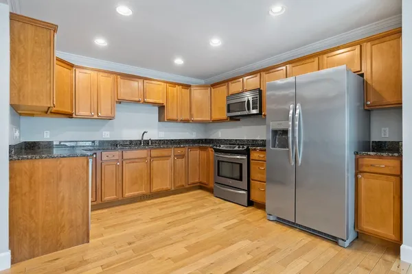 a kitchen with stainless steel appliances granite countertop a refrigerator a sink and a stove