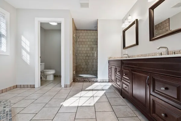 a spacious bathroom with a granite countertop sink a toilet and a mirror