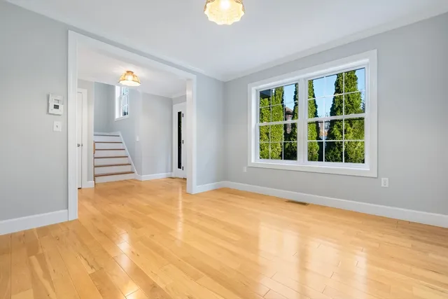a view of an empty room with wooden floor and windows