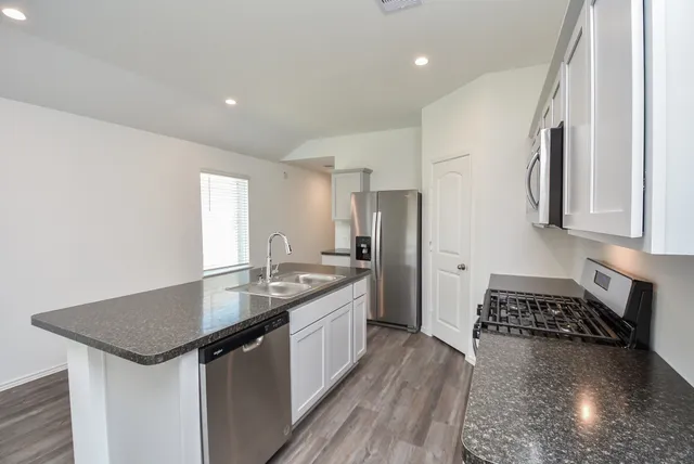 a kitchen with granite countertop a sink stove and refrigerator