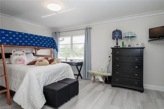 a bedroom with a bed and a flat tv screen on dresser