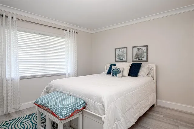 a bedroom with a bed and a dresser with wooden floor