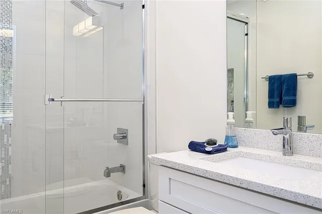 a bathroom with a granite countertop sink a mirror and shower