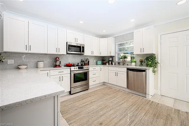 a kitchen with granite countertop a sink cabinets and stainless steel appliances