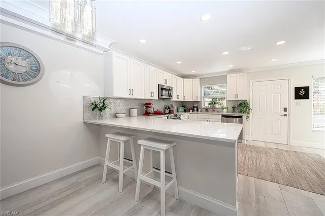 a kitchen with stainless steel appliances granite countertop a white cabinets and chairs
