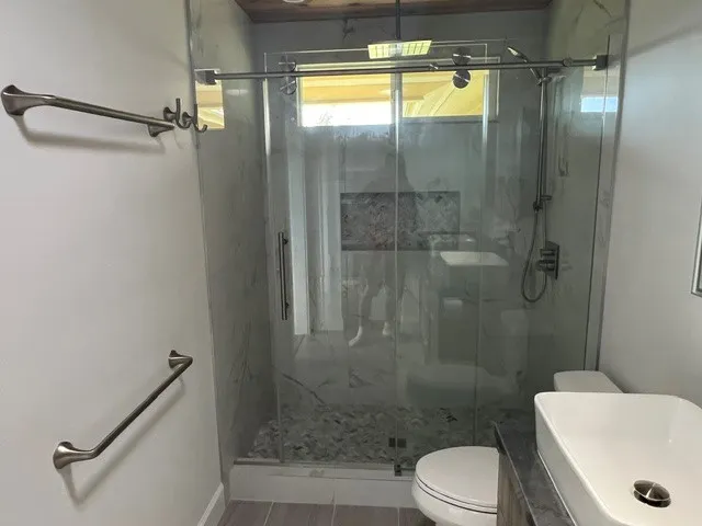 a bathroom with a granite countertop bathtub shower sink vanity and toilet