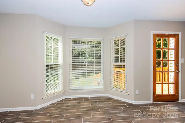 a view of an empty room with wooden floor and windows